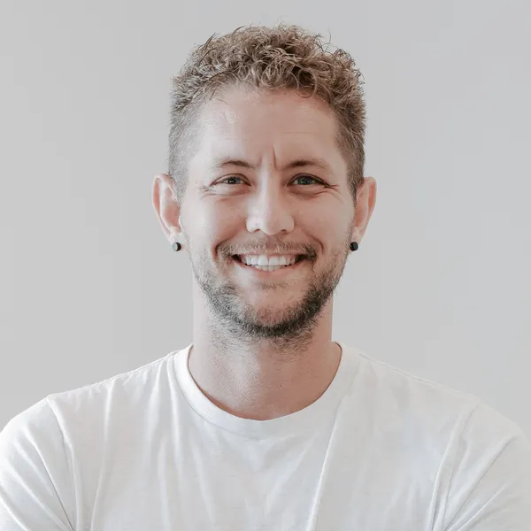Close-up of Joshua Shaw smiling, in a white tee, against a light background.